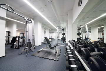Empty modern fitness center with dumbbell set, sport equipment