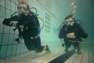 Two young women are diving with equipment in the pool