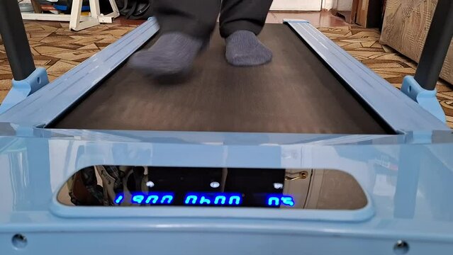 Man on treadmill walking fast, legs closeup, time lapse. Cardio training at home
