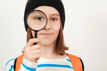 Portrait of student boy with magnifier. School, learning and development concept. Boy looking through magnifying glass.