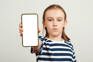 Young boy holding mobile phone with white blank screen in hand. Gadget with empty free space for mock up.