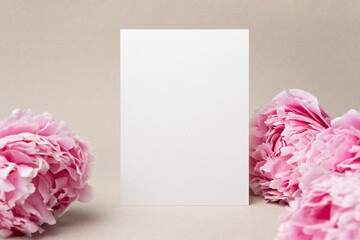 Invitation or greeting card mockup with fresh peony flowers, blank card with copy space