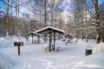Public, summer picnic areas covered with snow. Barbecue grills in winter park.