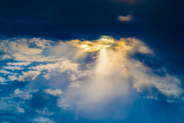 A pillar of sunlight comes from a gap in the clouds. Dark sky with a ray of light. Background on...