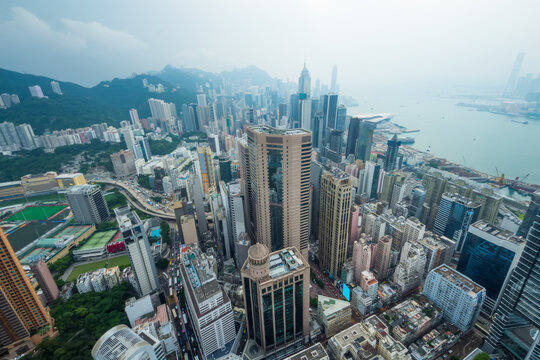 Skyscrapers, office buildings, coast in Hong Kong city, China at cloudy day, aerial view from Manulife Plaza
