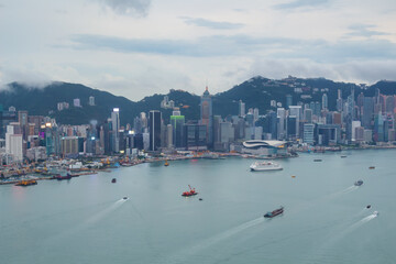 Skyscrapers on sea shore in business area, ships at cloudy day in Hong Kong, China, view from...