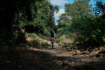 Obraz premium A middle aged bearded cyclist riding his gravel bike in the woods.