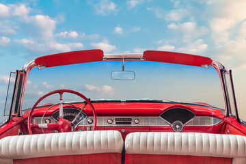 Driver view of a red vintage classic open American cabriolet car in front of a sunny blue sky - 755739309