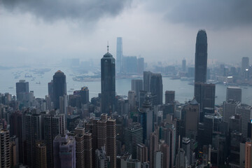 Fototapeta na wymiar Skyscrapers, sea shore with ships, dark clouds in business area in mist in Hong Kong, China, view from Queen Garden