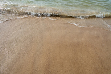 This image captures the simplicity and calmness of gentle waves lapping against a sandy shore. The...