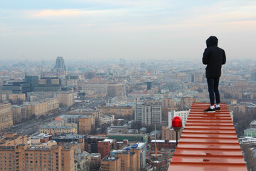 Back of roofer in black and evening cityscape with modern buildings