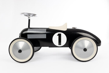 Retro style black toy car on white background. Toy car for riding in playing room. Childhood...