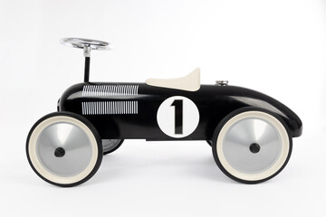 Retro style black toy car on white background. Toy car for riding in playing room. Childhood concept.