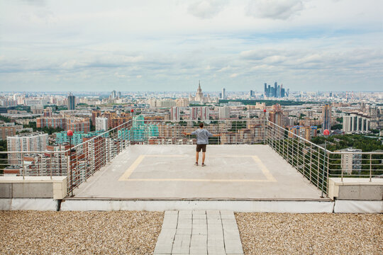 Man stands on roof of high building with railing at summer day in Moscow, Russia