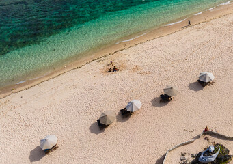 Aerial view of sandy beach and umbrella in Melasti Beach, a tropical beach, famous tourist destination located in Bali Island, Indonesia.