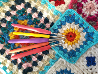 Crochet hook on a background of threads and a knitted square