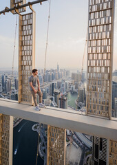 Roofer poses on concrete cross beam of Cayan Tower (Infinity Tower) in Dubai, UAE
