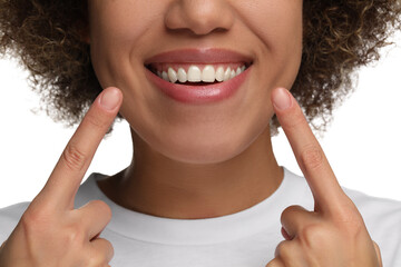 Woman showing her clean teeth and smiling on white background, closeup