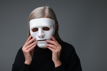 Multiple personality concept. Woman in mask on gray background, space for text