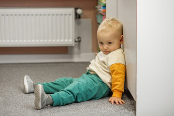 Naklejka premium Toddler Resting on Floor in Colorful Outfit