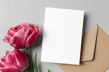 Fototapeta premium Blank wedding invitation card mockup with envelope and pink tulip flowers