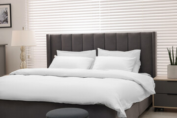 Fototapeta na wymiar Large bed and lamp in stylish bedroom. Interior design
