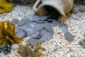 Old coins spilled out of a clay pot on the seabed