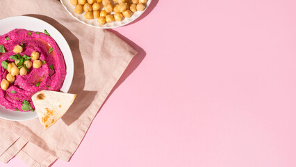 Beetroot hummus on pink background, top view and copy space