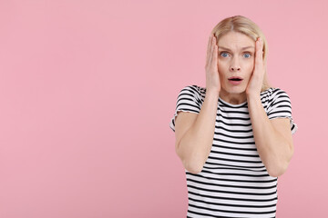 Portrait of surprised woman on pink background, space for text
