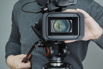 Videographer's hands bring camera into focus, cameraman's work, camcorder with wide-angle lens in...