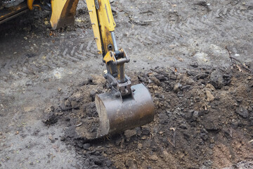 The excavator bucket begins to dig the ground at the construction site, the excavator begins...