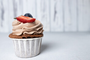 Chocolate cupcakes with cream cheese frosting, strawberry and blueberry on light background. Festive food for Saint Valentine's day, birthday dessert, wedding or baby shower girl. Copy space
