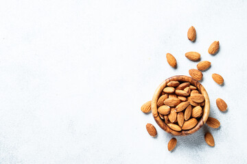 Almond nuts in wooden bowl at white background. Top view with space for text.
