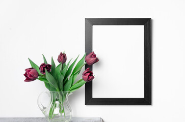 Vertical frame mockup on white wall with tulips