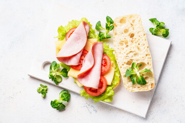 Sandwich with lettuce, cheese, tomatoes and ham. Healthy fast food or snack. Top view on white.