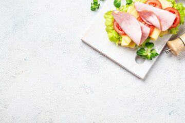 Sandwich with lettuce, cheese, tomatoes and ham. Healthy fast food or snack. Top view on white.