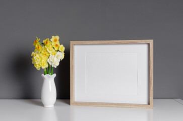 Blank wooden landscape frame mockup with flowers over grey wall, blank mock up
