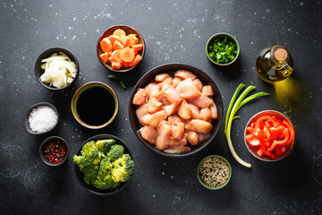 Chicken stir fry with soy sauce and vegetables at black background. Ingredients for cooking, recipe. Flat lay with copy space.
