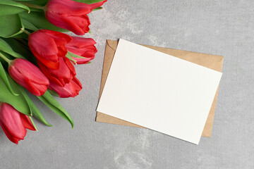 Greeting card mockup with red tulip flowers on grey concrete background, copy space