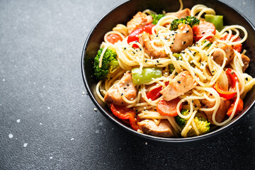 Stir fry chicken with vegetables and noodles at black background. Asian cuisine. Close up.