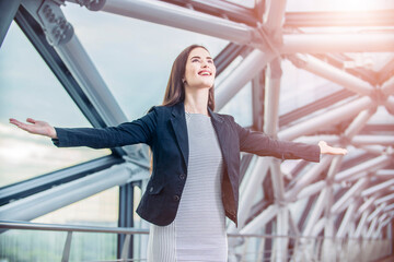 A beautiful businessman woman spreading her arms as a symbol of freedom against the background of a modern office building