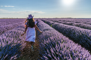 Young girl running between lavender bushes in the  field. Brihuega, Spain. - 755782543