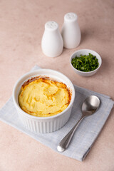 Shepherd's pie in a portioned white baking dish. Homemade traditional casserole (gratin) with minced meat and mashed potatoes. Selective focus, close-up.
