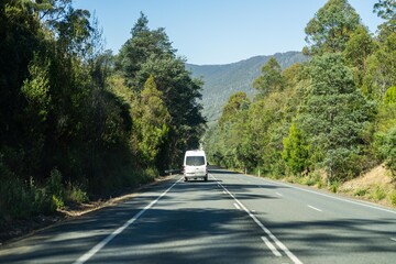 tourist traveling in a caravan exploring nature driving on a raod in the forest Cars Driving on a highway road, in australia - obrazy, fototapety, plakaty