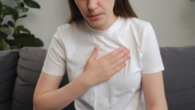 Close up of young woman have symptom gastroesophageal, esophageal, stomach ache and heartburn pain hand on chest from digestion problem after eat food. Acid reflux disease. Healthcare medical concept