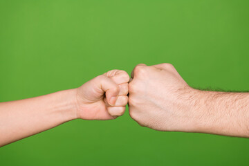 Photo of two female male arms bumping fists showing confrontation isolated green color background