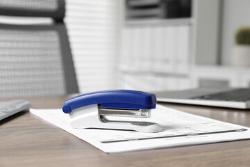 Bright stapler and document on wooden table indoors