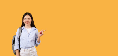 Confident woman pointing to side at free space, yellow backdrop, educational banner