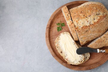 Tasty bread with butter and knife on grey textured table, top view. Space for text