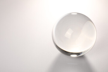 Transparent glass ball on light grey background. Space for text